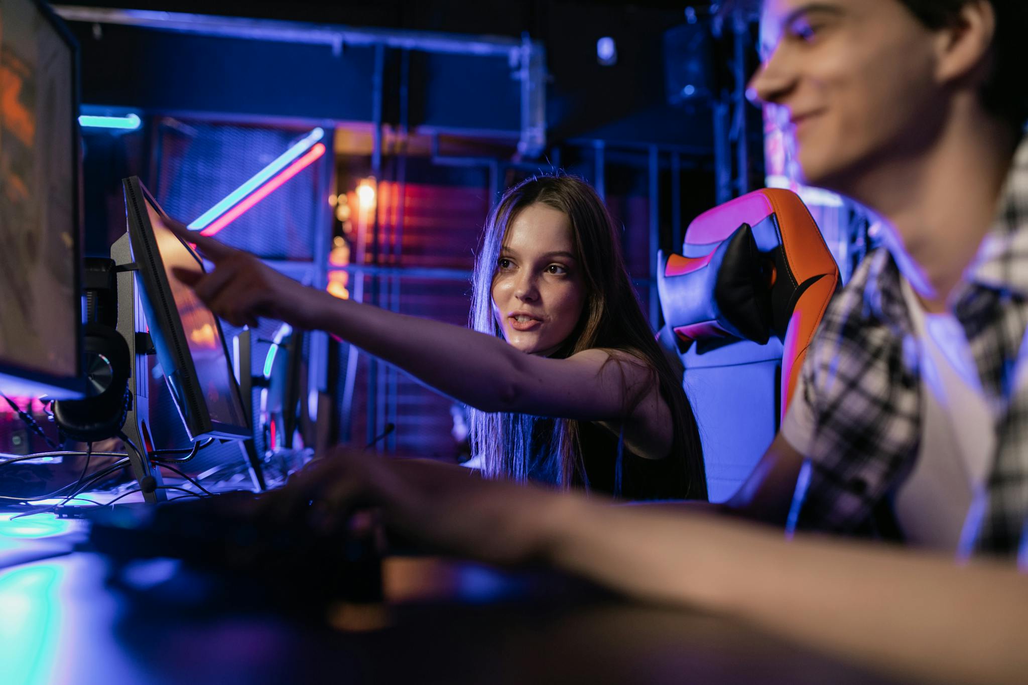 Teenagers engaging in a gaming session with illuminated monitors and vibrant LED lighting setup.